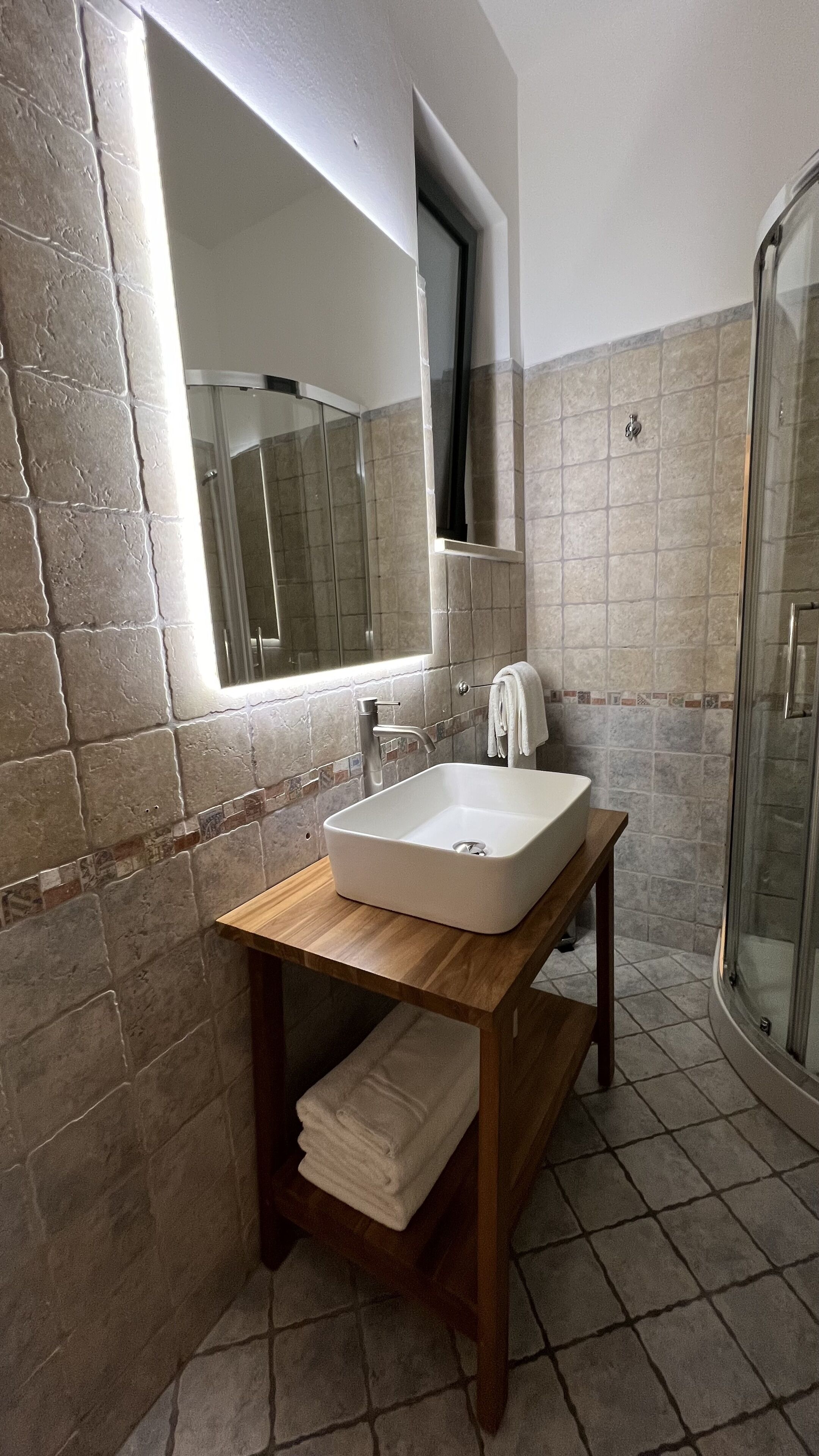 A bathroom with a sink, mirror, and shower.