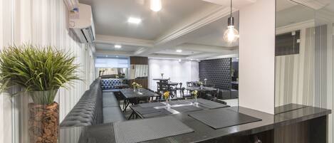 Una cocina moderna con encimera negra, taburetes de bar y una zona de estar con mesas y sillas.