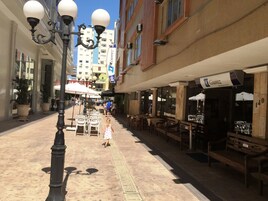 Una calle con mesas al aire libre, un farol y un edificio con un letrero.