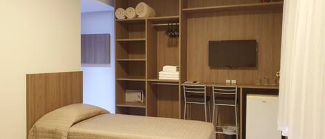 Habitación de hotel con dos camas, un escritorio, un televisor y un armario.