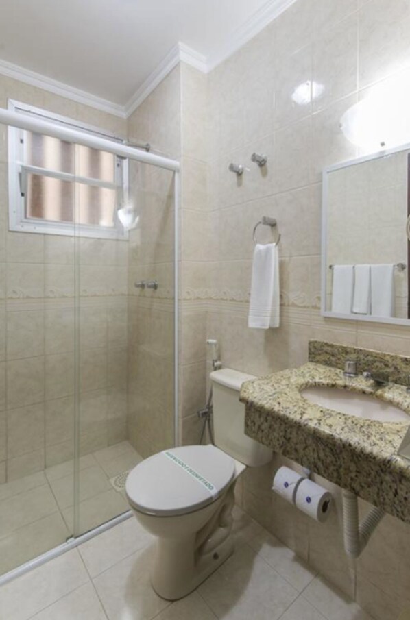 Un baño con ducha, inodoro, lavabo y espejo.