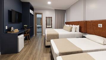 A hotel room with two beds, a desk with a chair, a television, and a small kitchenette.