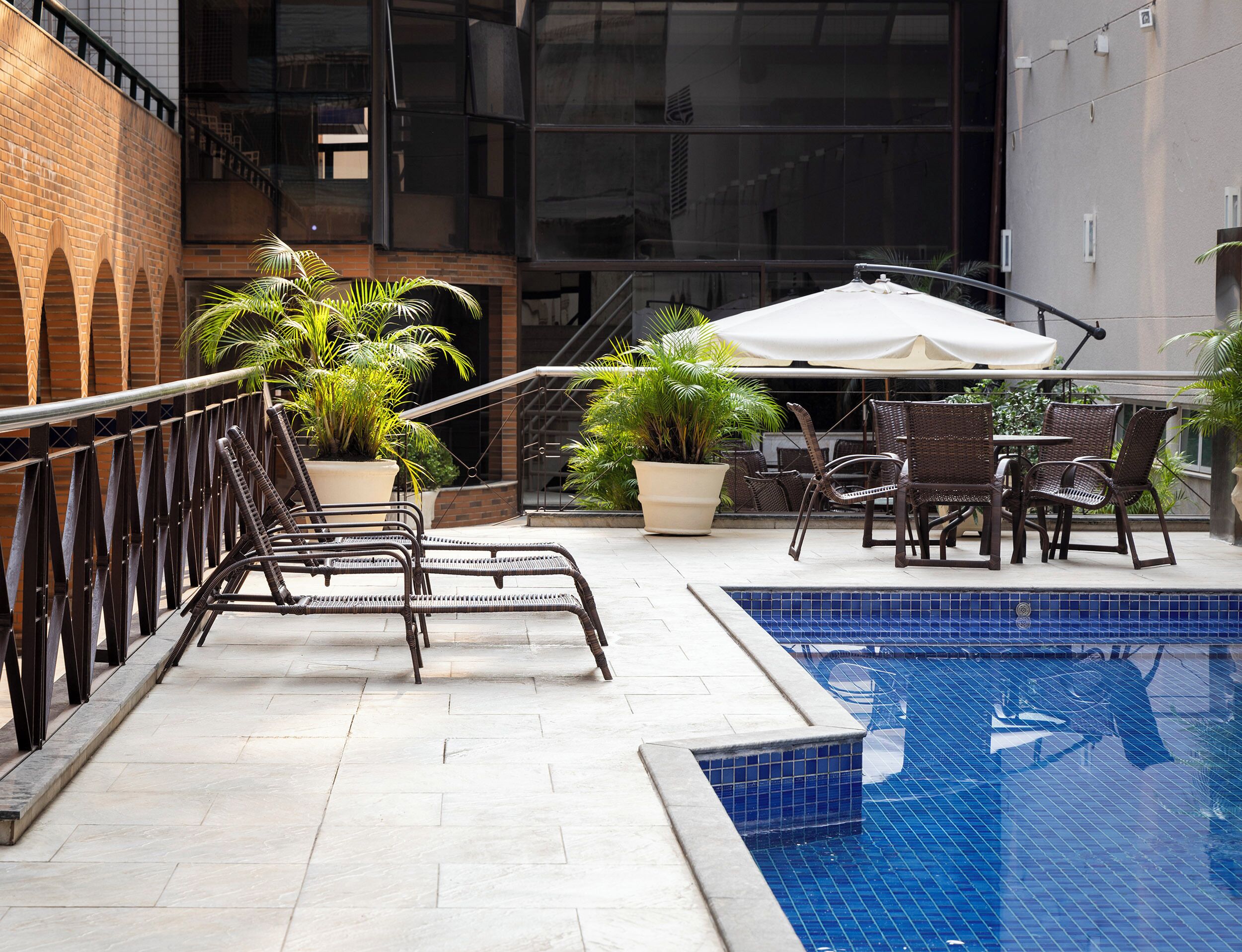 Un espace aménagé au bord de la piscine, avec des chaises longues, une table et des plantes en pot.