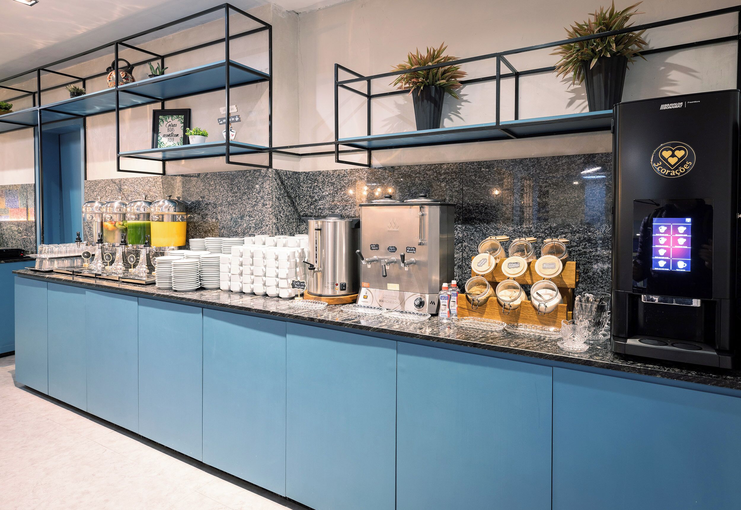 A modern kitchen with blue cabinets, a granite countertop, and various appliances including a coffee machine and a refrigerator.