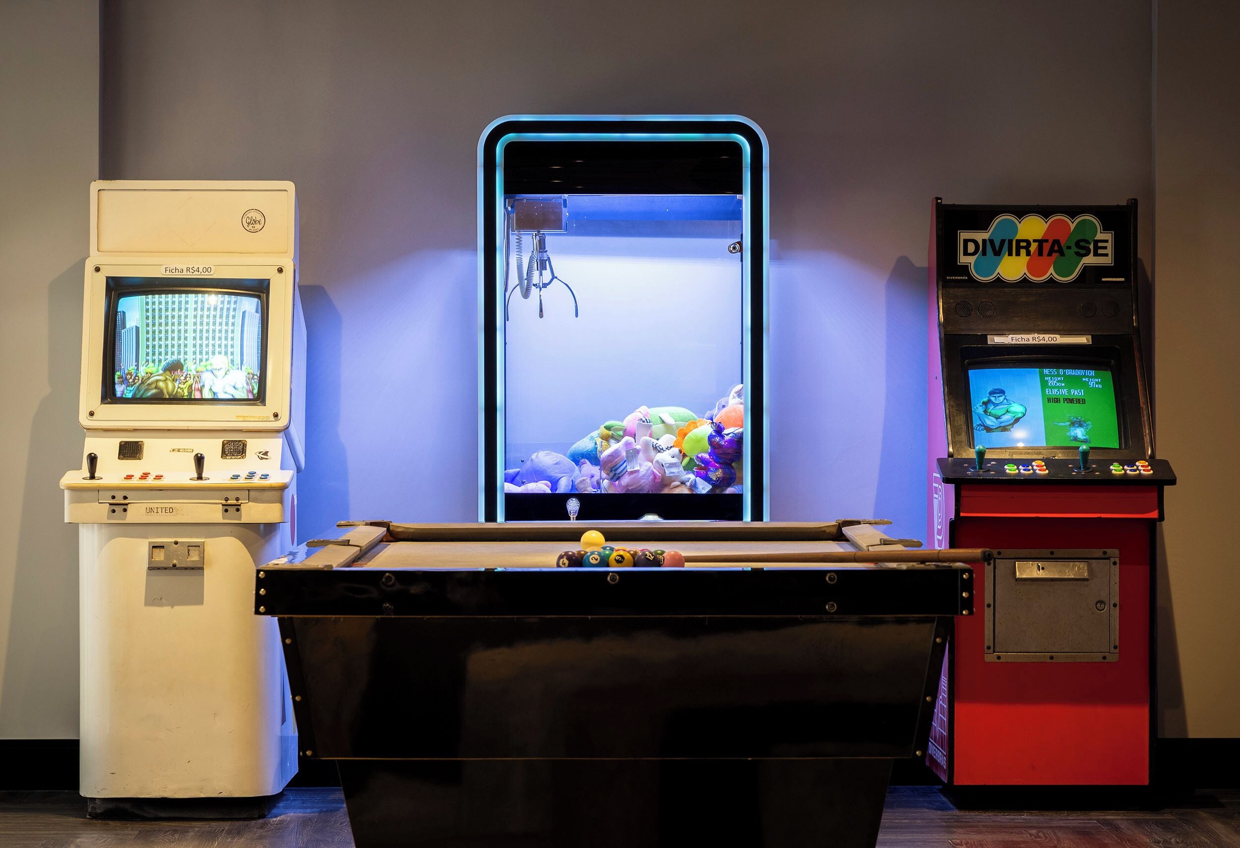 A pool table with a video game machine and a vintage television.