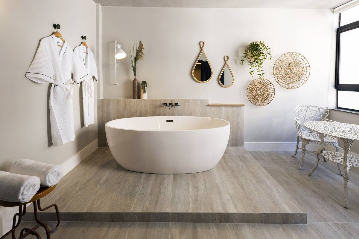 Une salle de bain moderne avec une baignoire sur pieds, un meuble-lavabo en bois et une table ronde avec des chaises.