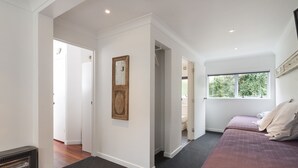 A hotel room with a large window, a bed, a heater, and a door leading to another room. - Lakeside City Apartments (Rotorua)