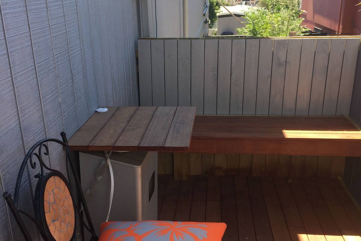 A wooden deck with a bench and a chair with a cushion.