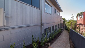 A residential building with a grey exterior, a narrow pathway, and a wooden fence. - Lakeside City Apartments (Rotorua)