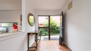 A hallway with a wooden floor, a mirror, a small table, and a door leading outside. - Lakeside City Apartments (Rotorua)
