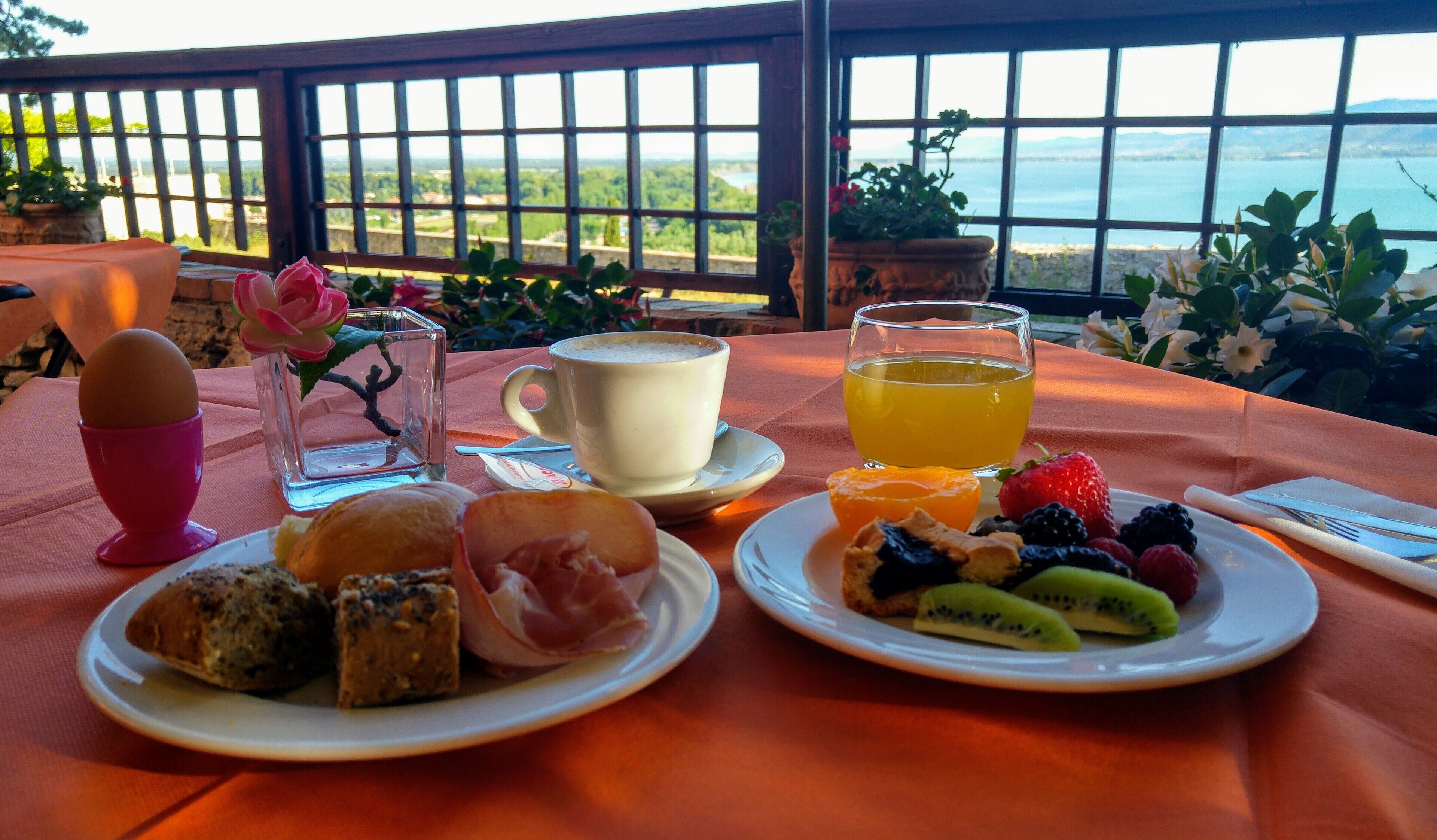 Uma mesa posta para o café da manhã, com pratos de comida, uma xícara de café e um copo de suco.