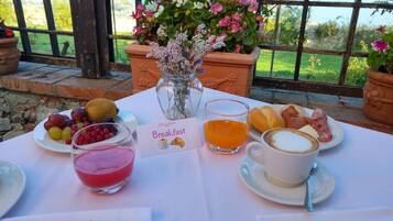 Une table de petit-déjeuner avec une variété de fruits, un verre de jus d’orange, une tasse de café et une assiette de viennoiseries.