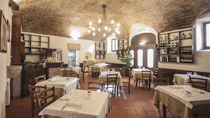 Un restaurant avec de nombreuses tables dressées, un bar à vin fixé au mur et un plafond en briques au style rustique.