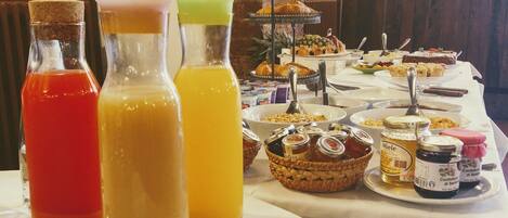 Uma mesa de buffet com diversos alimentos, incluindo frutas, doces e acompanhamentos.
