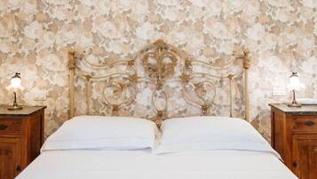 Un letto con carta da parati a motivi floreali, una testiera in legno e lampade da comodino.