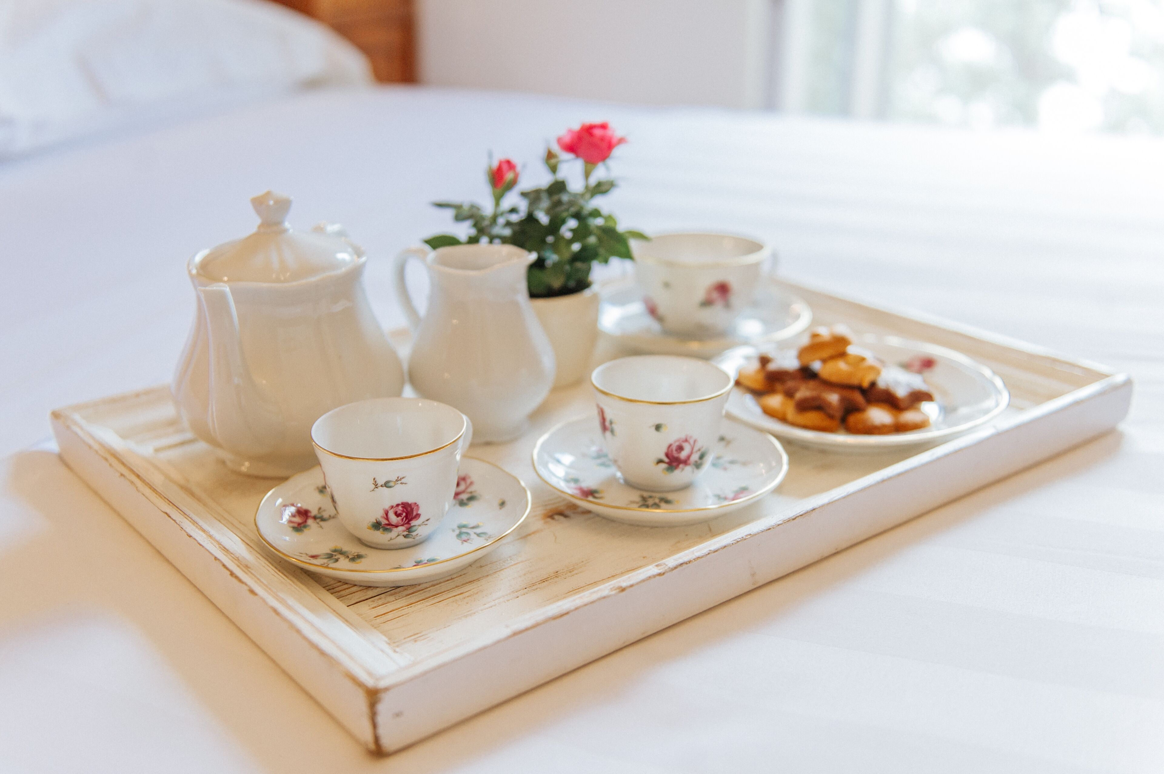 A tray with tea set and pastries on a bed.