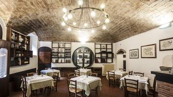 A restaurant with brick walls, wooden tables, and a chandelier.