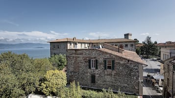 Ein Steingebäude mit einer Terrasse mit Blick auf ein Gewässer und Berge.