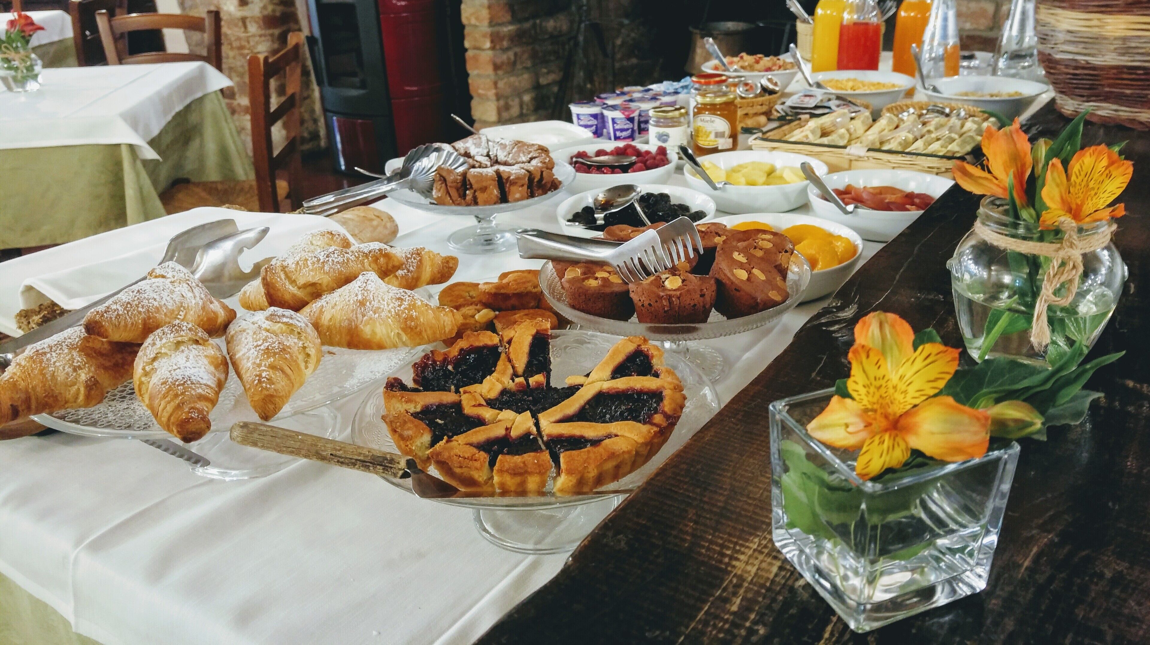A buffet table with various pastries, fruits, and condiments.
