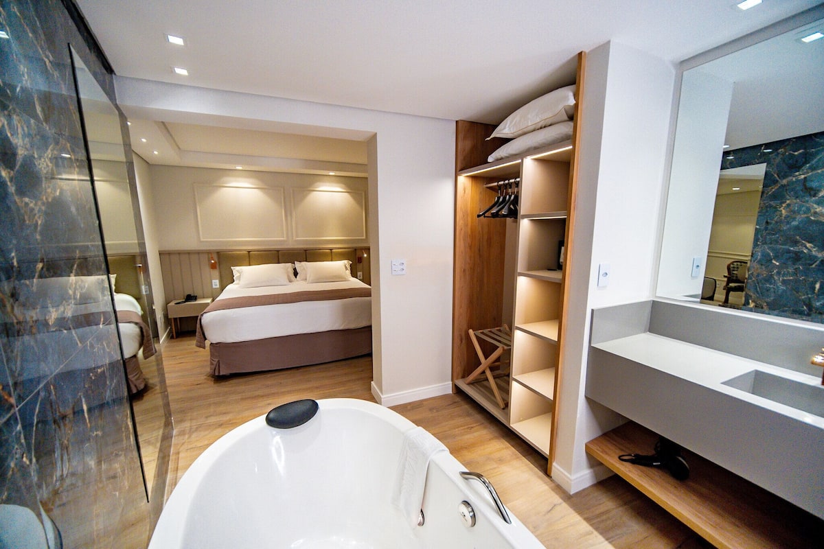 Un baño moderno con una bañera grande, ducha a ras de suelo y tocador de madera.