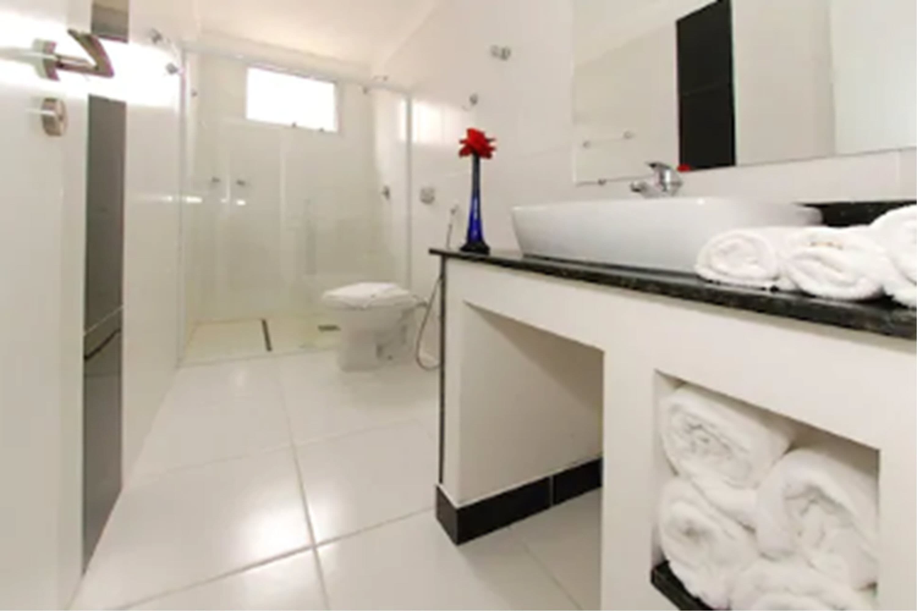 Casa de banho moderna com lavatório branco, espelho e porta-toalhas.