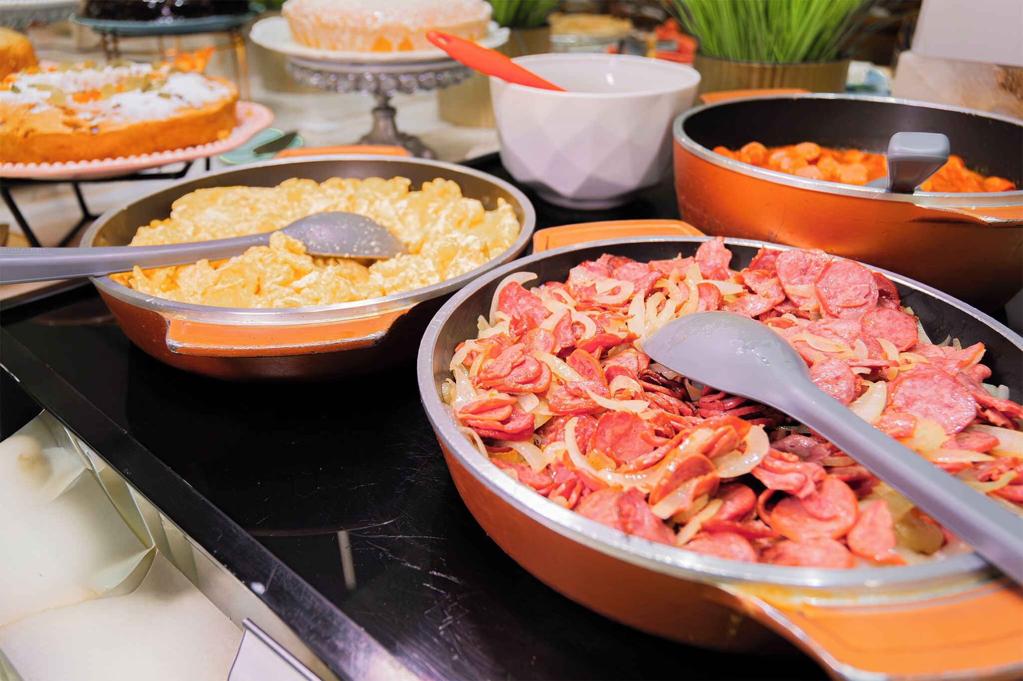 A buffet table with various dishes, including a large bowl of sliced meat and a bowl of scrambled eggs.