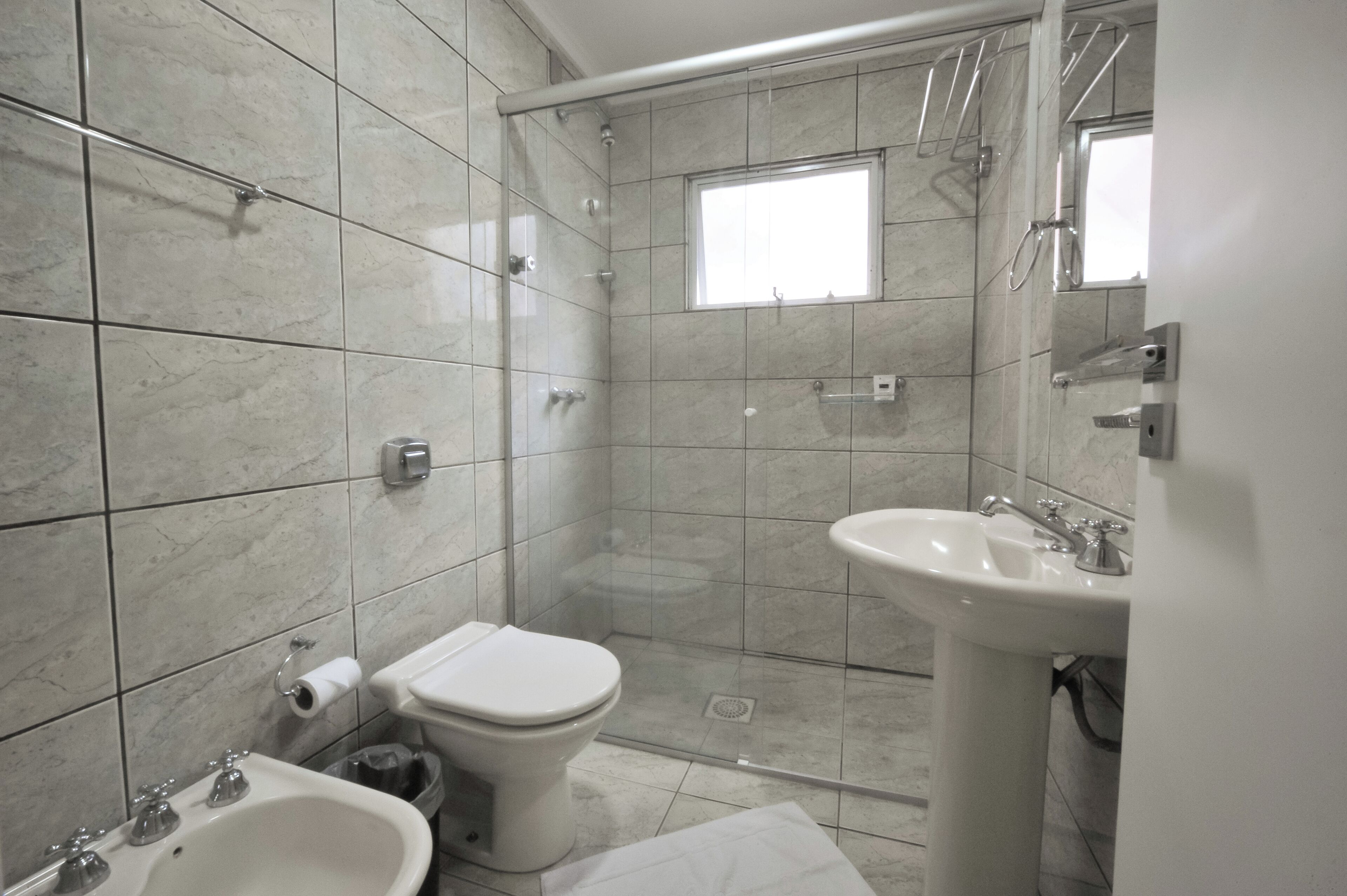A bathroom with a shower, toilet, bidet, and sink.