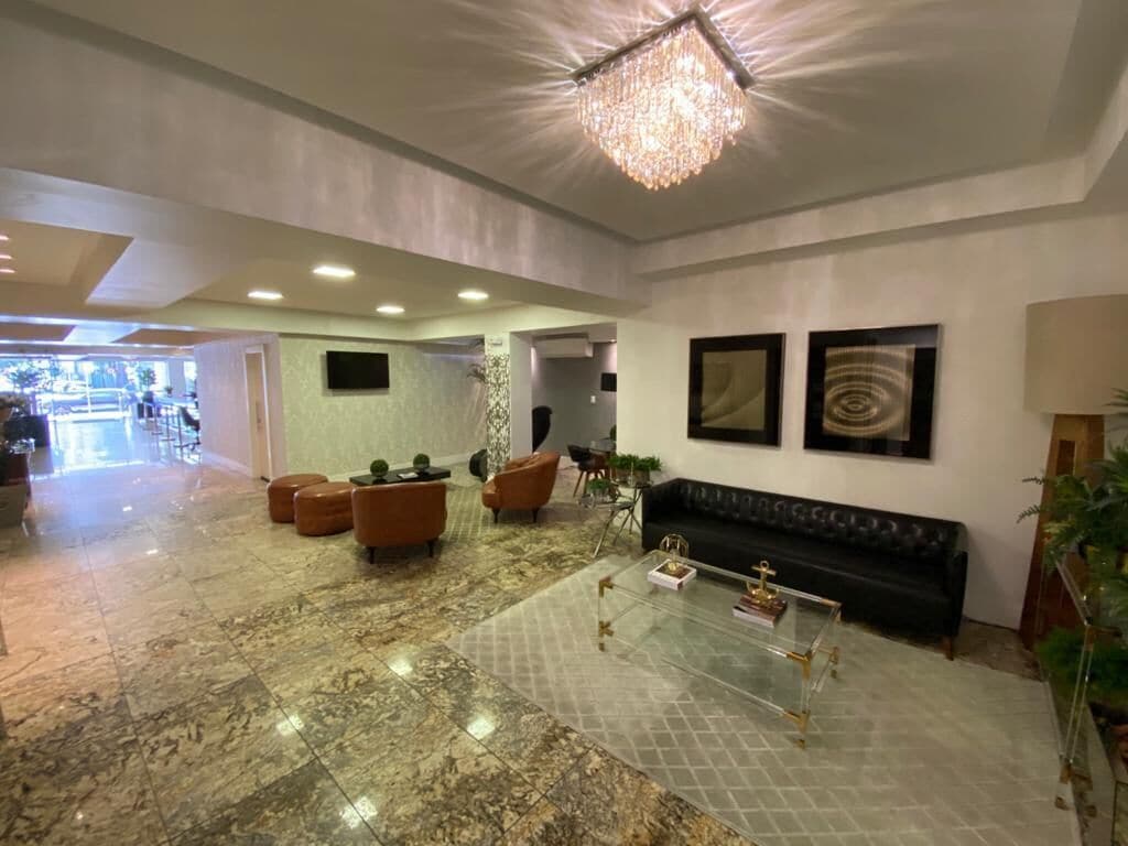 A spacious lobby with a marble floor, leather seating, a glass coffee table, and a chandelier.