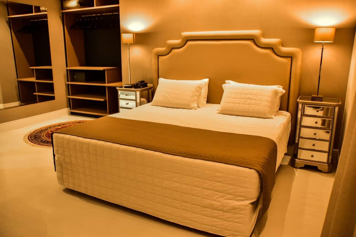 Un dormitorio ordenado con una cama grande, mesitas de noche, un armario y un guardarropa.