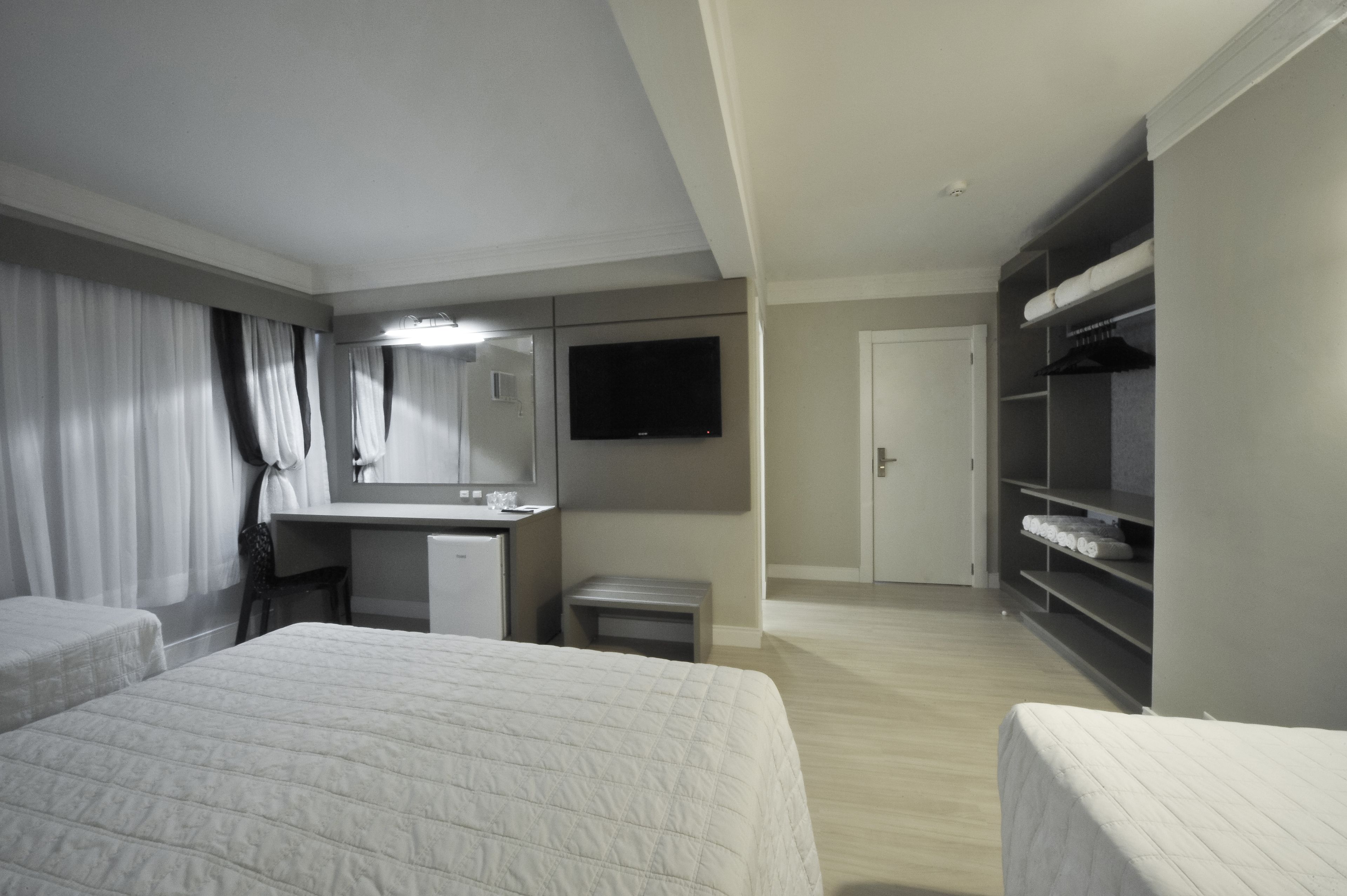 Habitación de hotel con dos camas, un escritorio, un televisor y un armario.