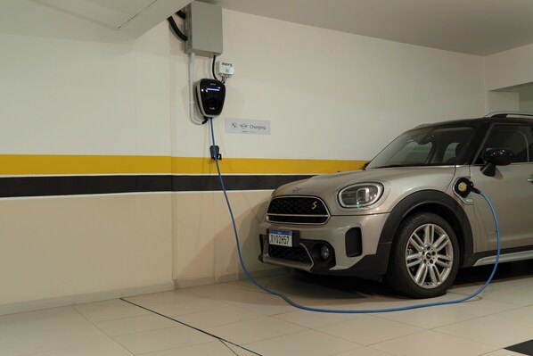 A car charging in a parking garage with a sign indicating the charging station. - Hotel Marimar The Place (Balneário Camboriú)