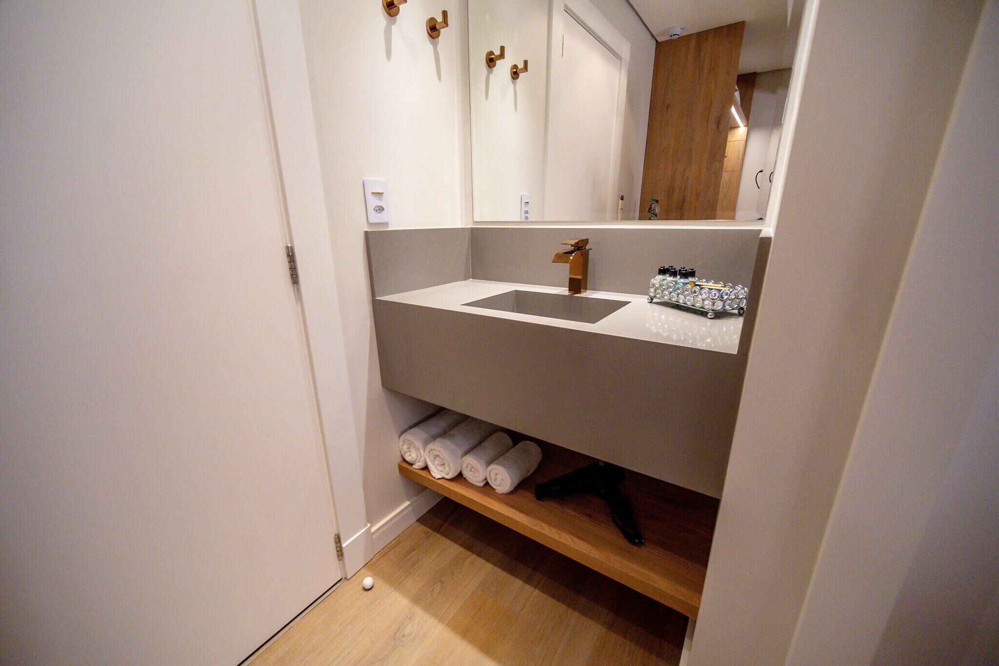 A bathroom with a white sink, wooden shelves, and a mirror.