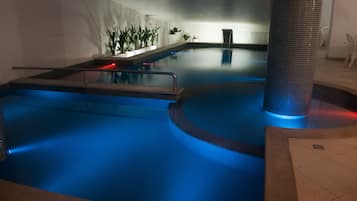 A swimming pool with a blue-lit edge, a tiled floor, and potted plants along the wall.