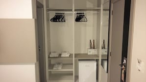 A walk-in closet with hanging storage, shelves, and a small refrigerator. - Hotel Palmas Executivo (Balneário Camboriú)