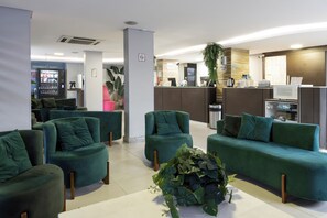 A modern lobby with green sofas, a coffee machine, and a reception desk. - Hotel Palmas Executivo (Balneário Camboriú)