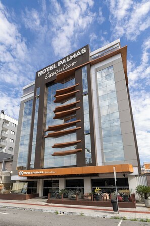 Un moderno edificio de hotel con un cartel llamativo que dice 'HOTEL PALMAS Ejecutivo'.