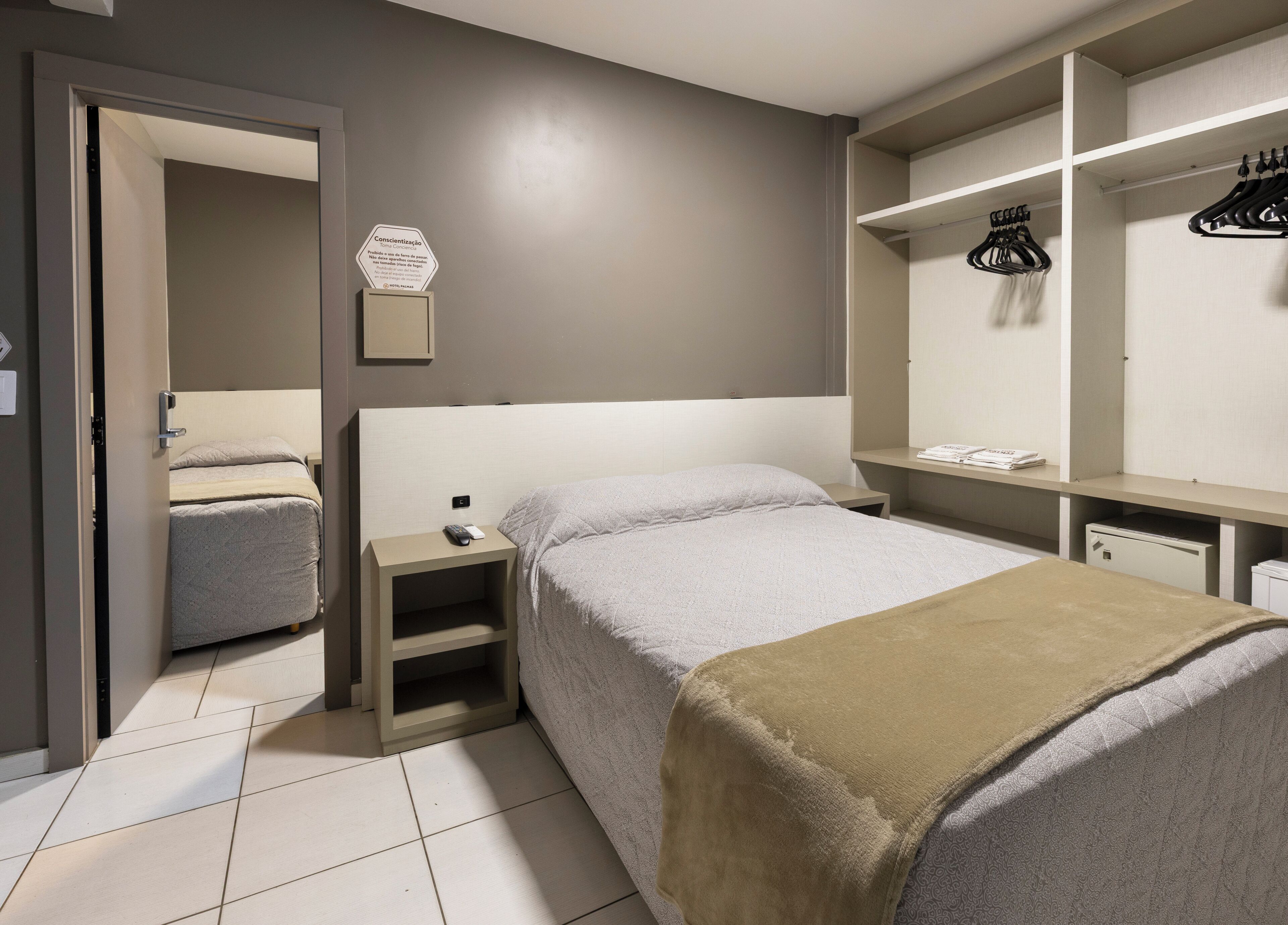 Et hotelværelse med en seng, et natbord og en garderobe med hængende tøj.