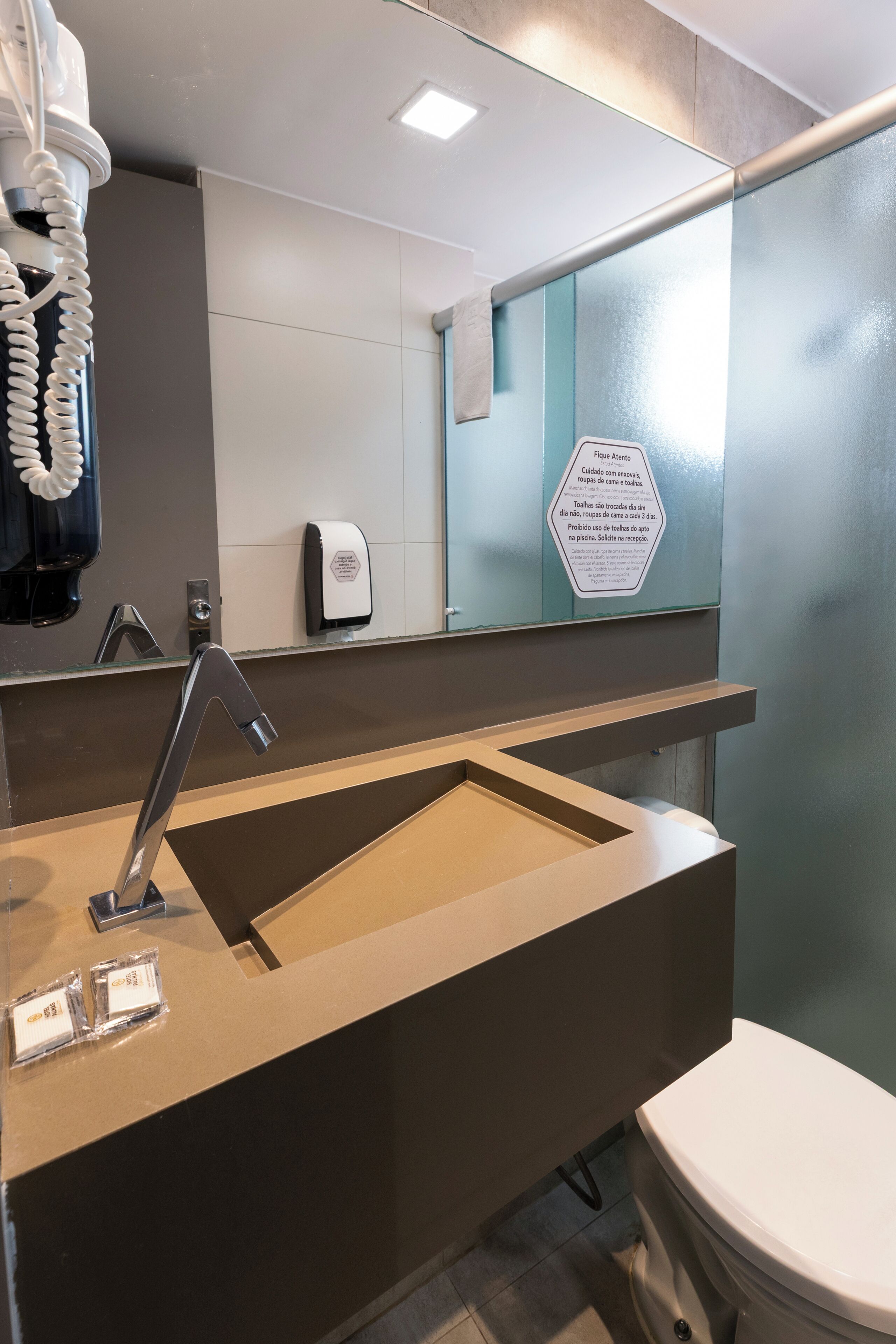 A modern bathroom with a large mirror, a sink, and a toilet.