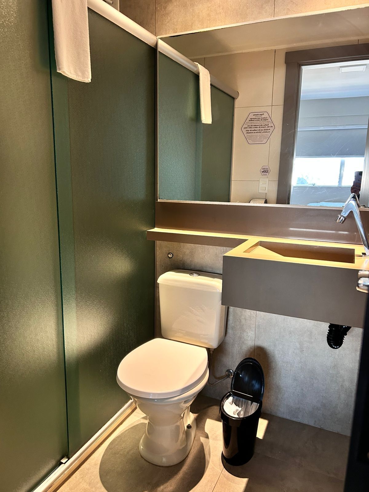 A compact bathroom with a toilet, sink, and a small trash bin.