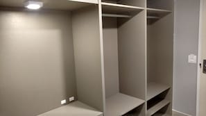 A closet with multiple shelves and a light fixture above. - Hotel Palmas Executivo (Balneário Camboriú)