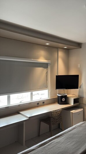 A modern room with a desk, a chair, a TV, and a window. - Hotel Palmas Executivo (Balneário Camboriú)