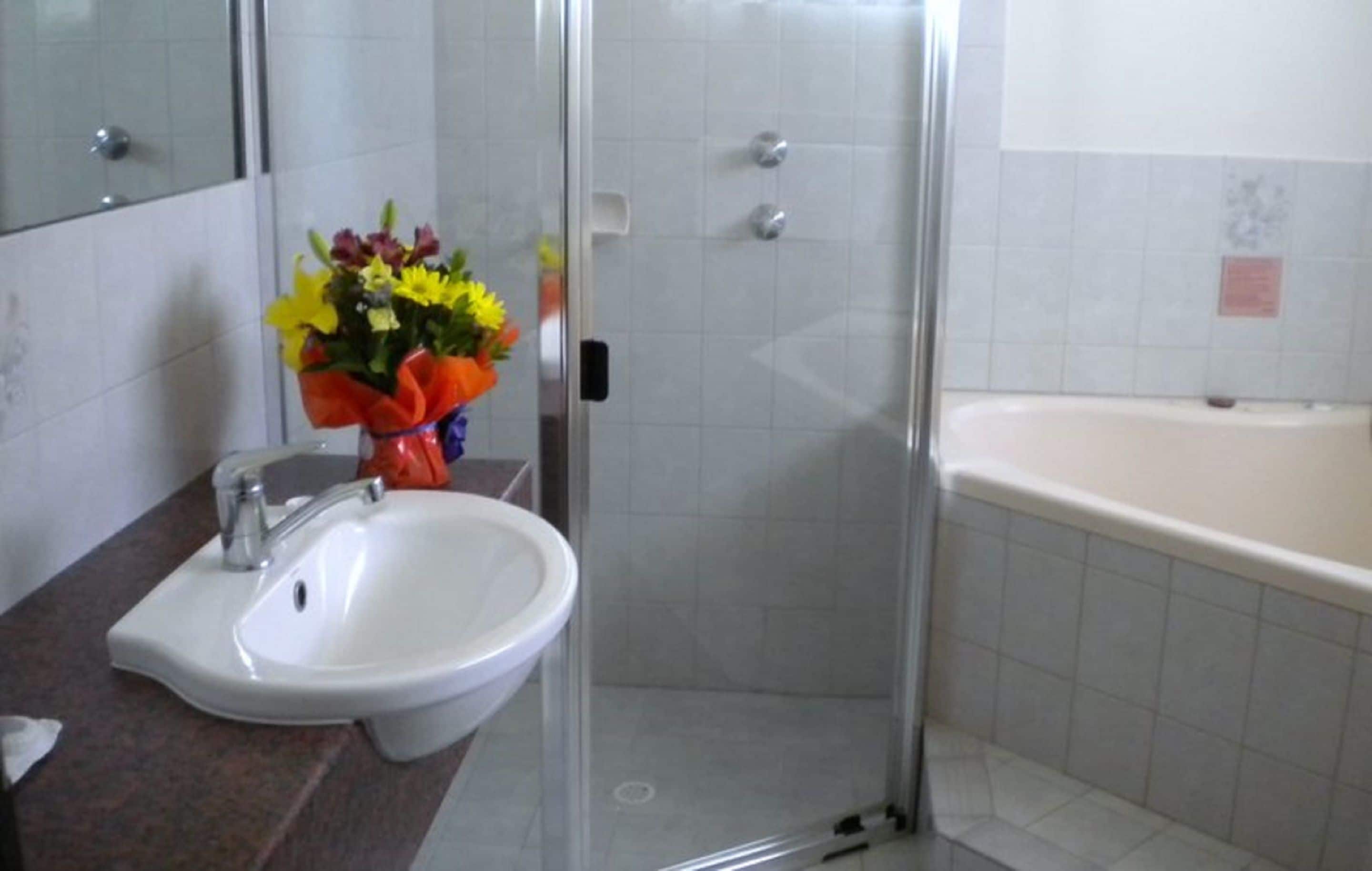 A bathroom with a white sink, a glass shower enclosure, and a bathtub.
