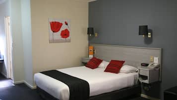 Habitación de hotel con cama, dos mesitas de noche, un teléfono y una lámpara de pared.