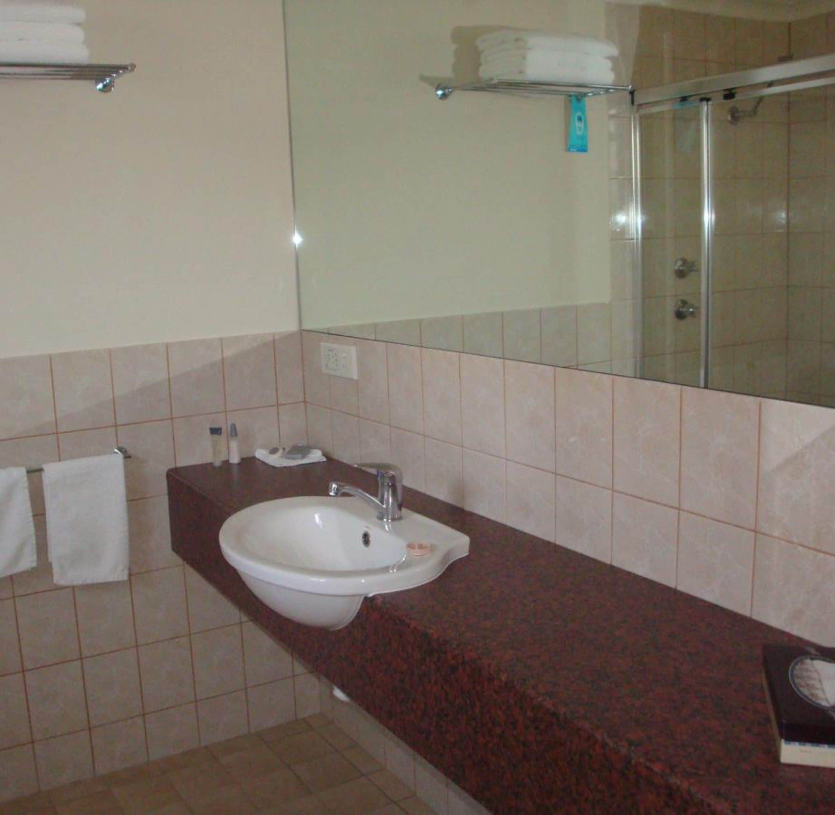 Un baño con lavamanos blanco, espejo y ducha.