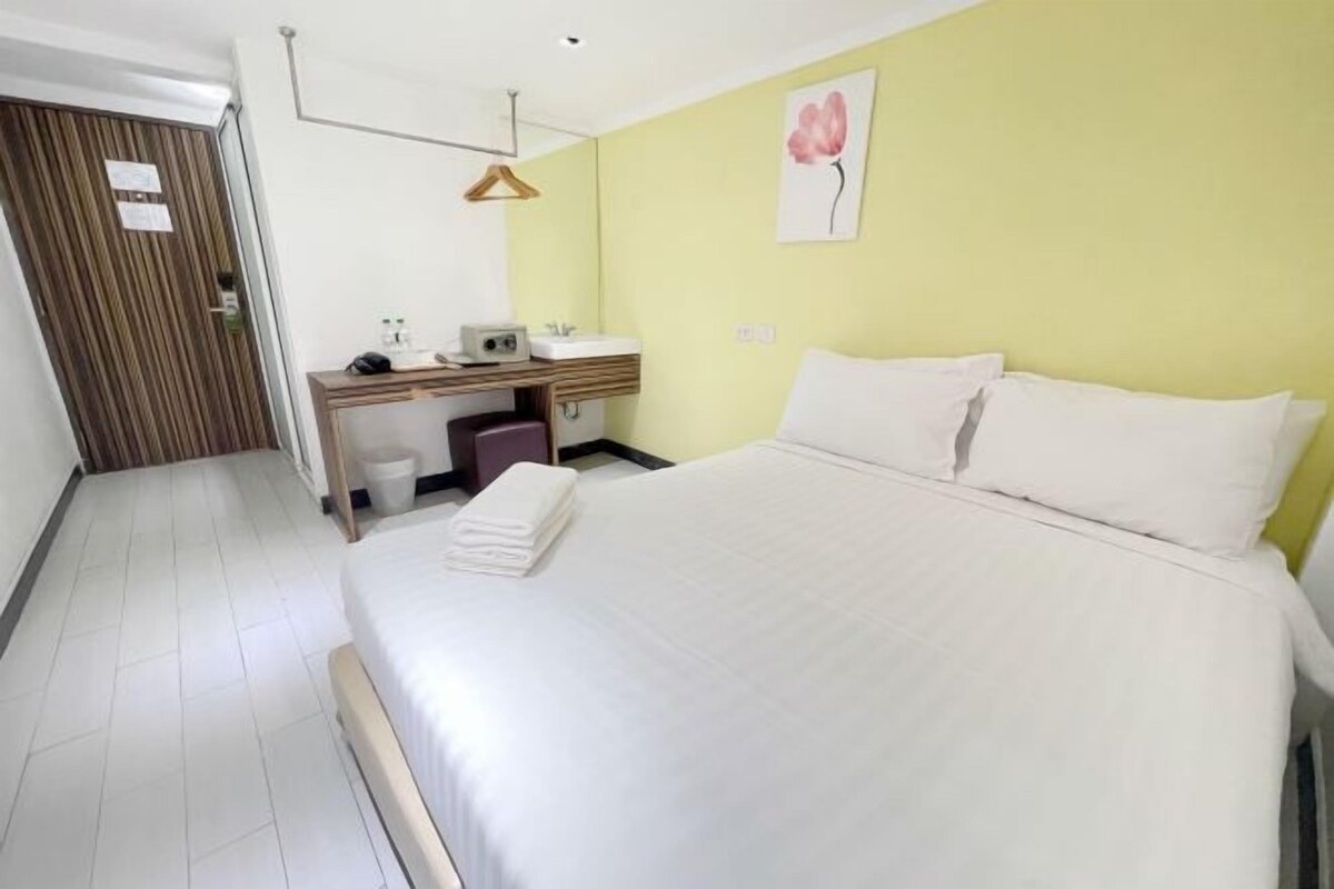 Habitación de hotel con cama, escritorio con silla, una mesita y un espejo.