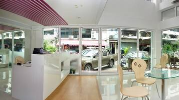 A modern reception area with a glass partition, a reception desk, and a seating area with chairs and a glass table.