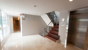 A modern hotel lobby with a glass corridor, a staircase, and a stainless steel elevator. - Nantra Ploenchit (Bangkok)