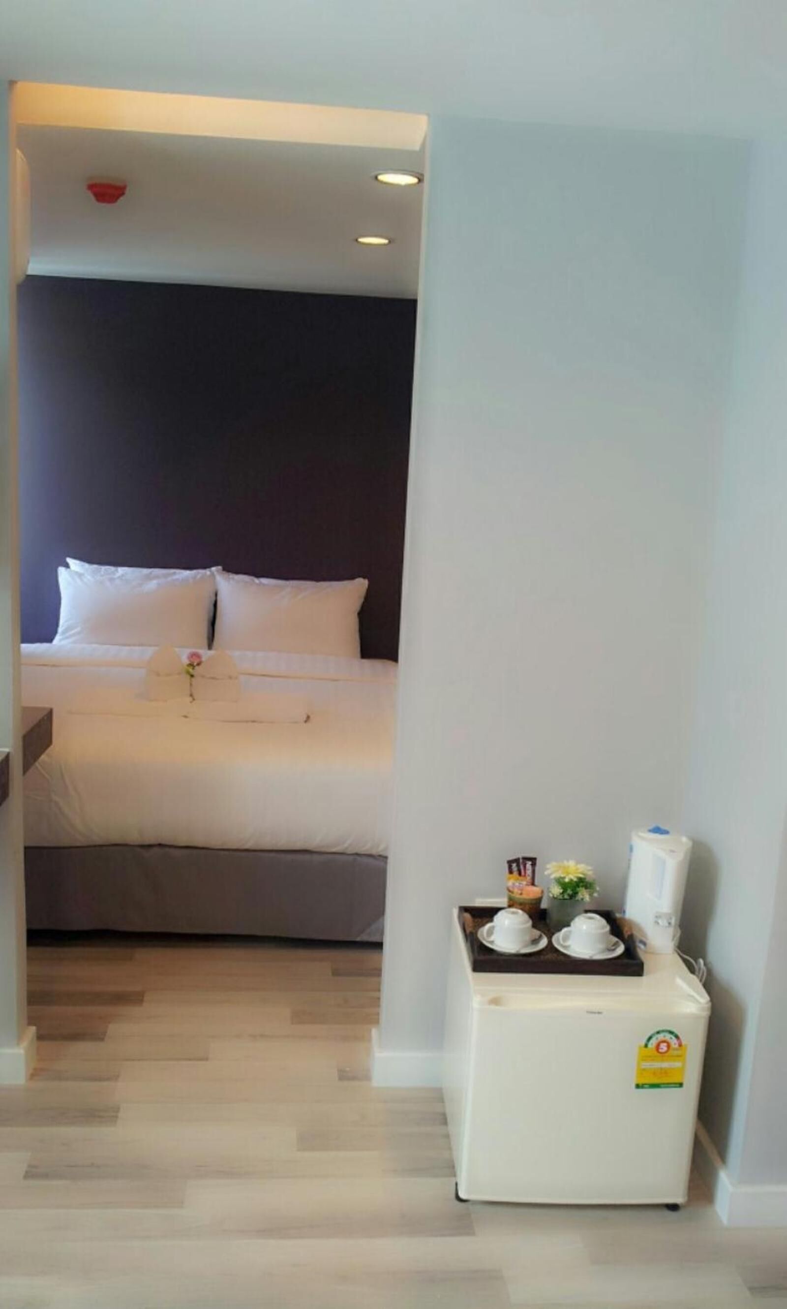 Ein Hotelzimmer mit einem Bett, einem kleinen Kühlschrank und einem Tablett mit Tassen und einer Blume.