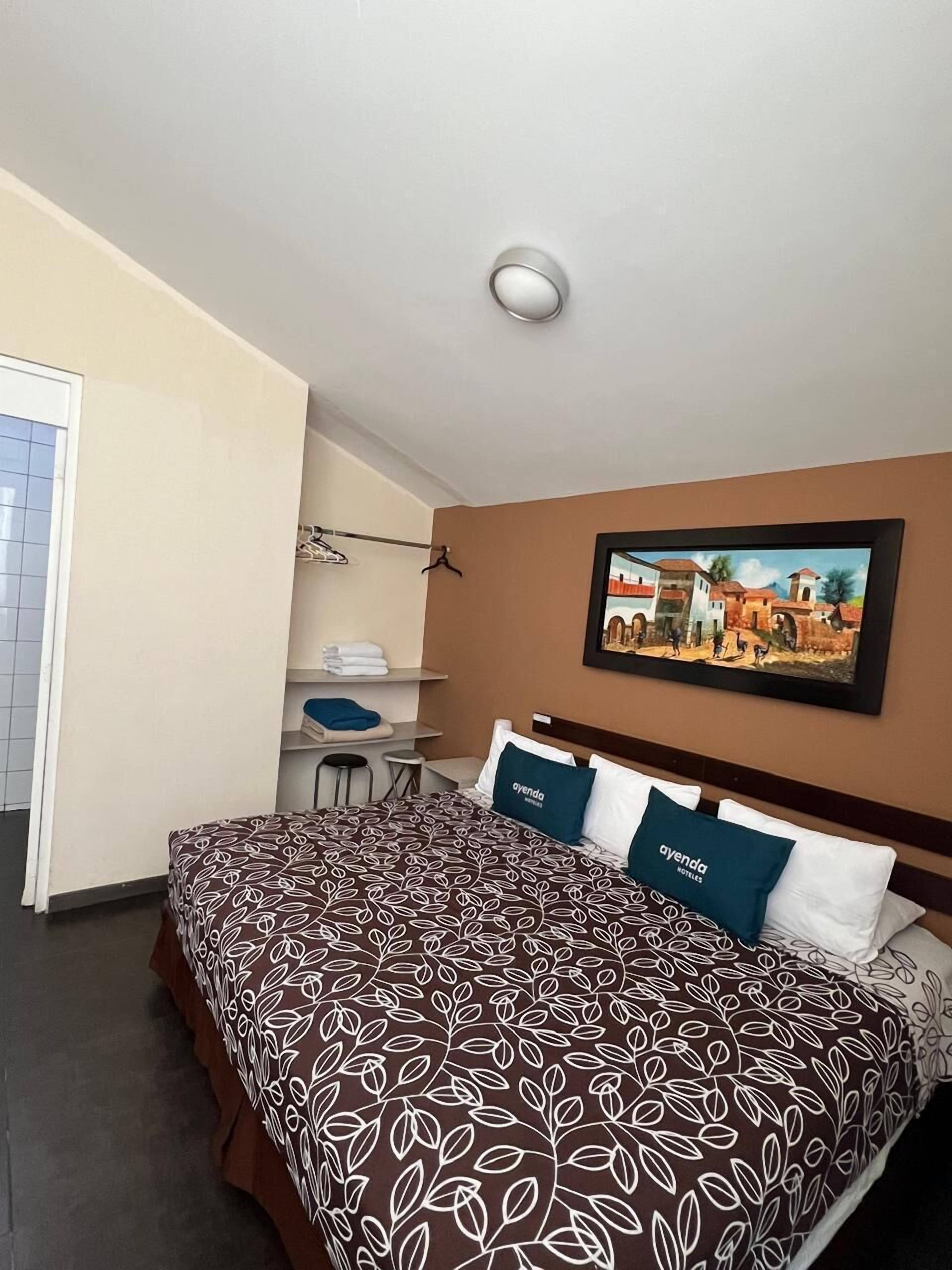 A hotel room with a bed, a desk, and a chair.