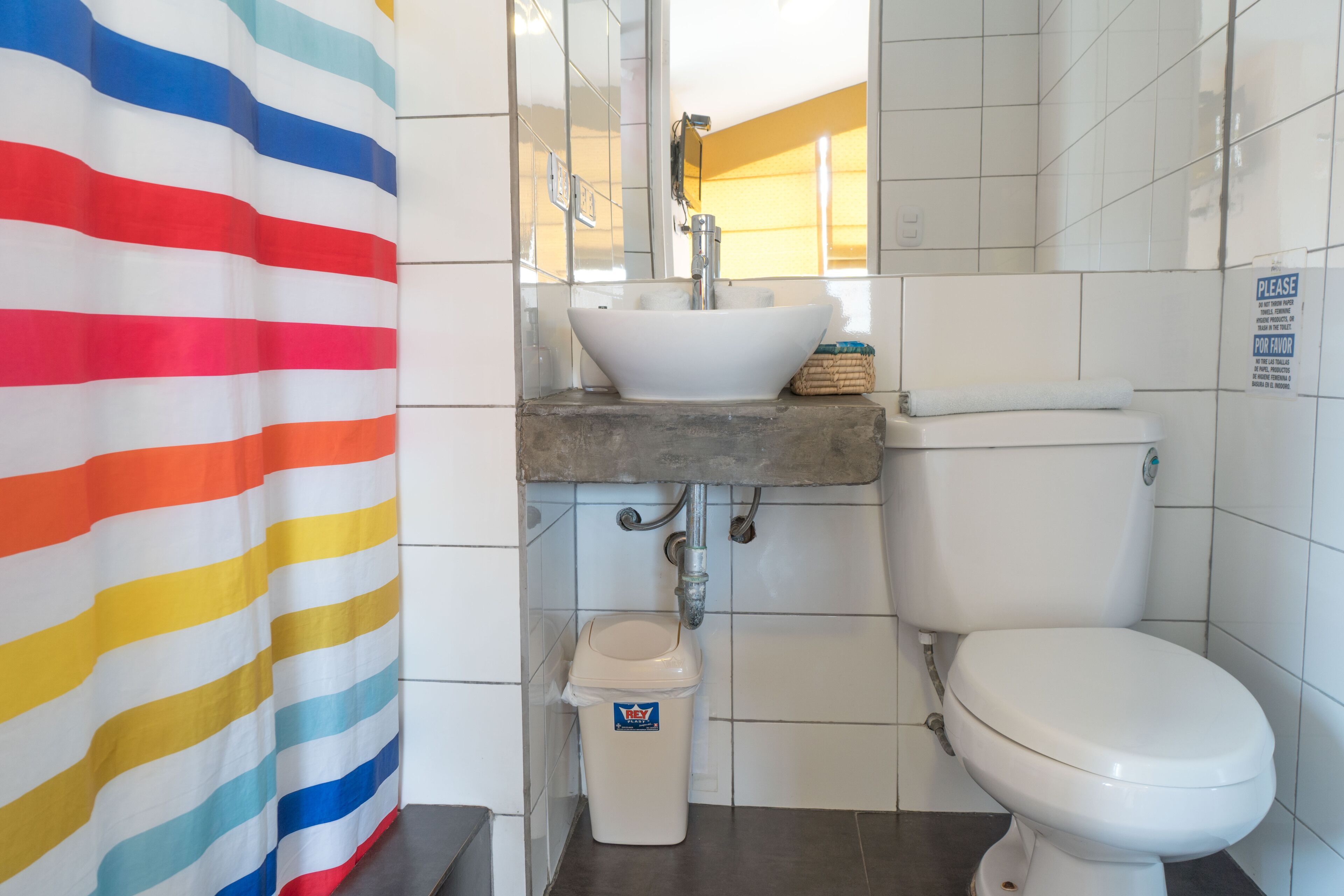 A bathroom with a white sink, toilet, and a striped shower curtain.